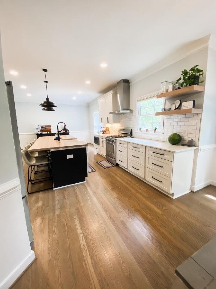 Modern kitchen interior featuring a large island, sleek cabinetry, and natural wood floors.