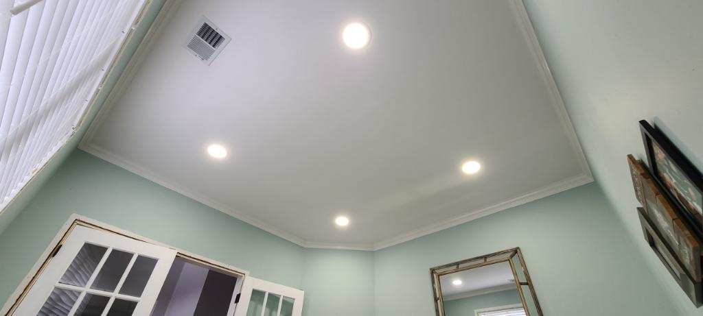 Ceiling with recessed lights in a mint green room with white trim and a mirror.