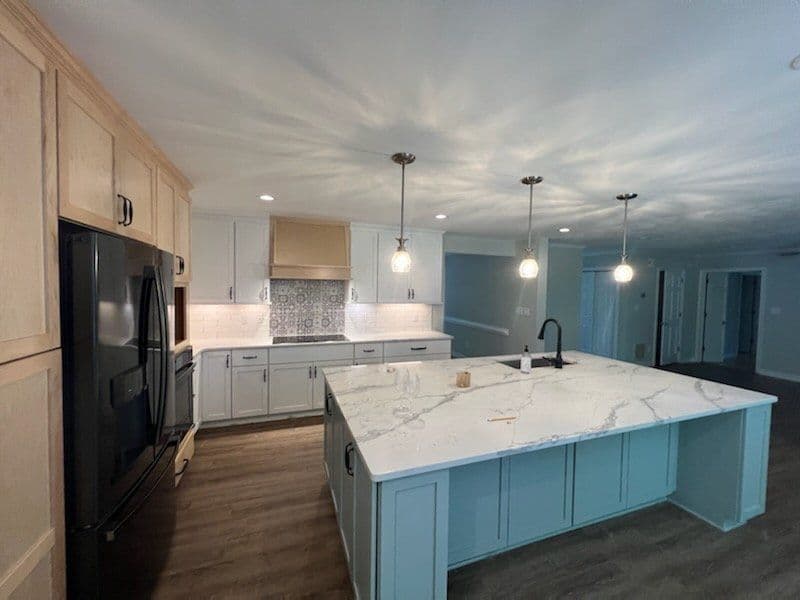 Modern kitchen with white cabinets, a large island, and stylish pendant lights.