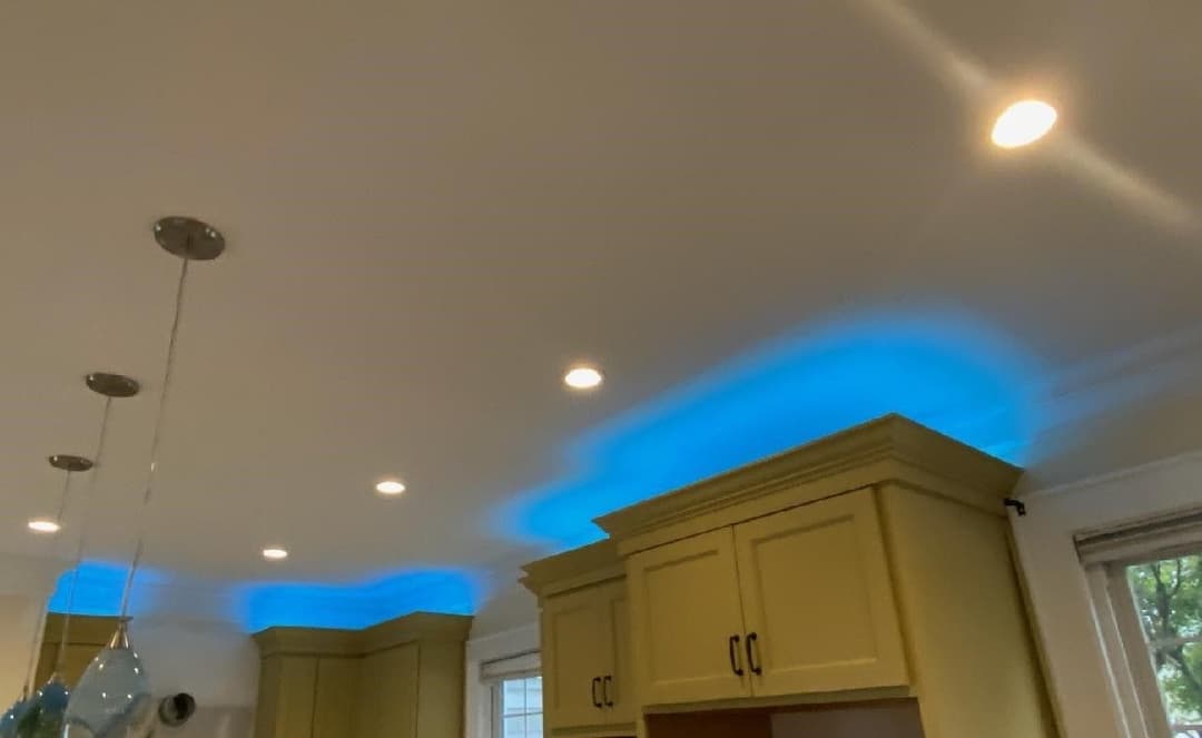 Modern kitchen with yellow cabinets and blue under-cabinet LED lighting.