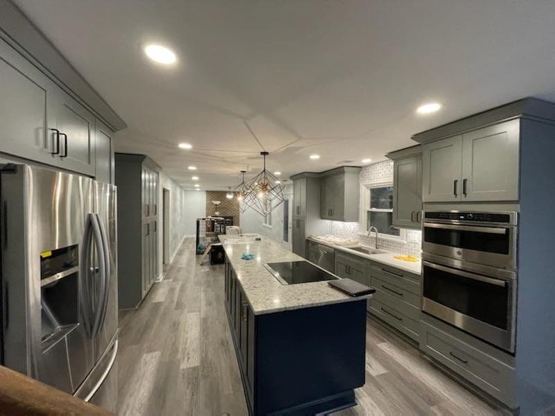 Modern kitchen featuring gray cabinetry, stainless steel appliances, and an island with seating.