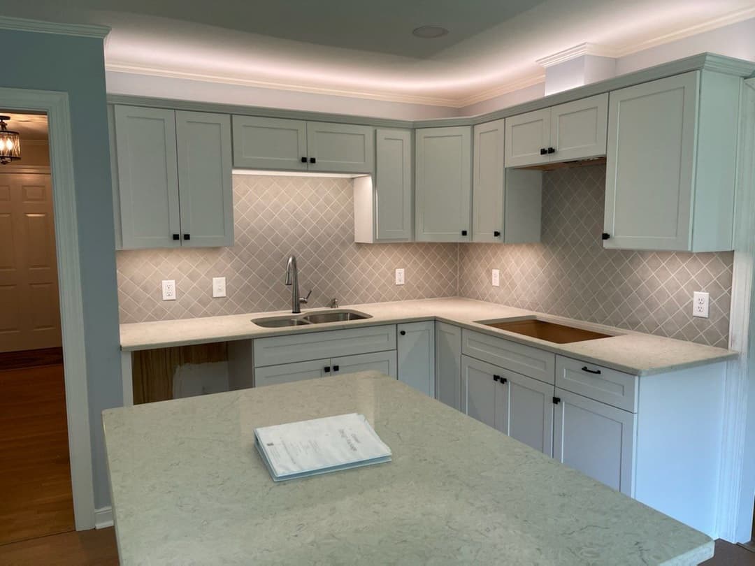 Modern kitchen design with white cabinetry, stone countertops, and stylish backsplash.