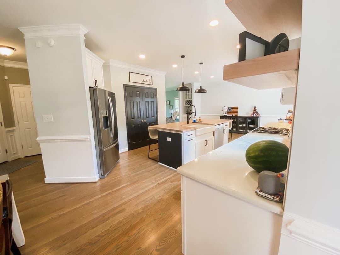 Modern kitchen with hardwood floors, black appliances, and a watermelon on the countertop.