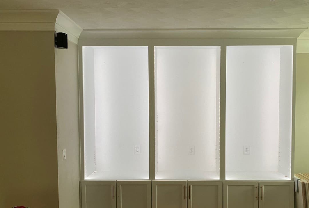 Three illuminated display shelves with white backing and built-in lighting in a modern interior.