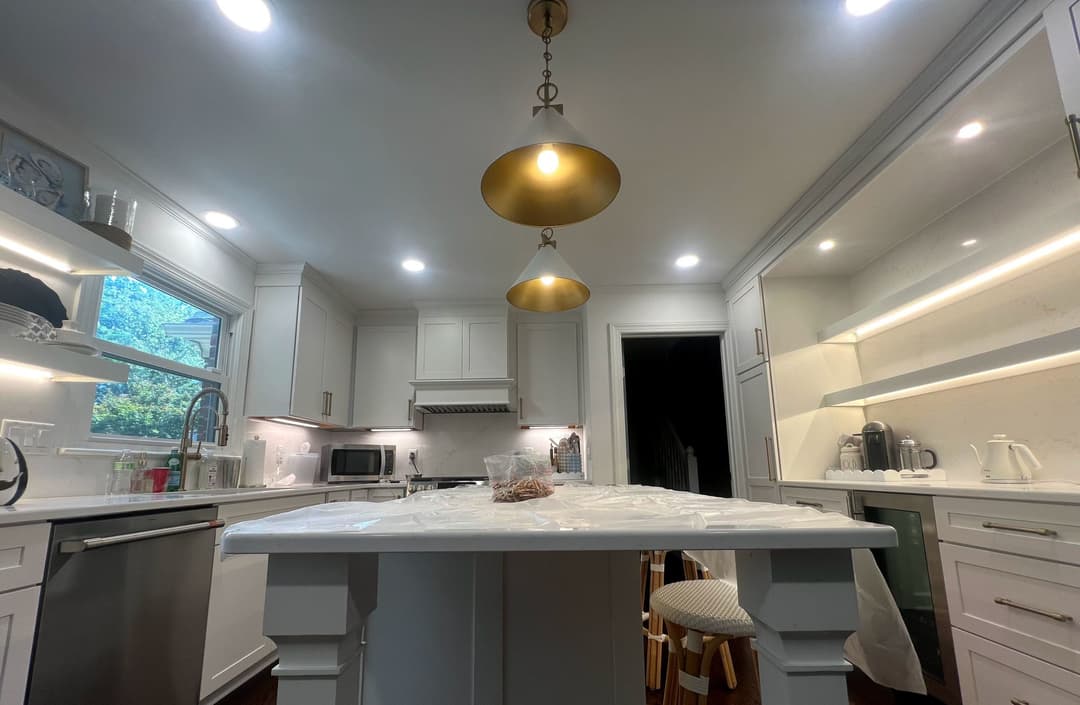 Modern kitchen with white cabinets, gold pendant lights, and a central island.