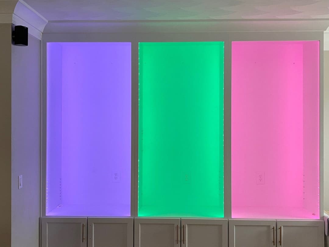 Colorful lit shelves in shades of purple, green, and pink showcasing modern interior design.