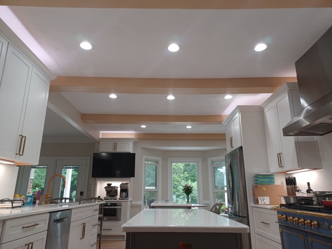 Modern kitchen with white cabinetry, large island, stainless steel appliances, and natural light.
