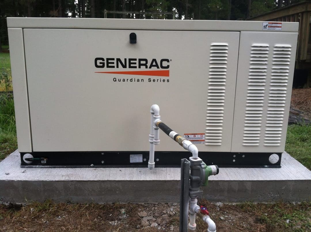 Generac Guardian Series generator with connections, installed on a concrete base outdoors.